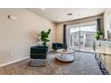Comfortable living room with stylish teal chairs, a round coffee table, and a sliding glass door leading to a balcony at 6153 N Ceylon St # 303, Denver, CO 80249