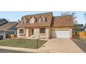 Traditional brick home with an attached garage and mature trees, showcasing a blend of comfort at 3873 W 98Th Ave, Westminster, CO 80031