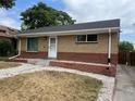 Quaint brick house featuring a classic design with a well-kept lawn and a paved driveway at 1283 Lipan Dr, Denver, CO 80221