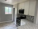Modern kitchen with stainless steel appliances, white cabinets, and stylish tile backsplash at 1283 Lipan Dr, Denver, CO 80221