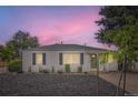 Inviting single-story home with fresh landscaping and a cozy front porch at dusk at 5090 Tejon St, Denver, CO 80221