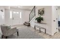 Welcoming entryway with white trim, hardwood floors, black and white rug and a modern staircase at 5203 Scranton St, Denver, CO 80239
