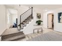 Hallway with stairs, wood floors, neutral carpet, white walls, and modern black handrail at 5203 Scranton St, Denver, CO 80239