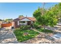 A well-maintained red brick house with lush greenery, mature trees, and inviting curb appeal at 11349 Downing Dr, Northglenn, CO 80233