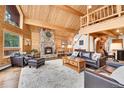 Spacious open living room with wood paneled walls, stone fireplace, and comfortable seating at 387 Pine Dr, Idaho Springs, CO 80452