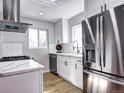 Bright kitchen featuring stainless steel appliances, white cabinets, light countertops, and wood-look flooring at 3033 Leyden St, Denver, CO 80207