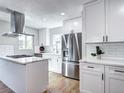 Modern kitchen boasts stainless steel appliances, sleek white cabinets, and a stylish range hood over the island at 3033 Leyden St, Denver, CO 80207