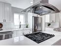 Bright kitchen with stainless steel appliances, white countertops and cabinets, with overhead lighting and decorative hood at 3033 Leyden St, Denver, CO 80207