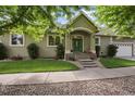Home's exterior boasts a well-manicured lawn, complemented by mature trees and a charming front porch at 1235 S Balsam St, Lakewood, CO 80232
