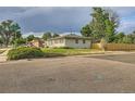 Exterior shot of a single-story home with a fenced yard and lush landscaping in a neighborhood setting at 2996 S Sheridan Blvd, Denver, CO 80227