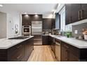 Modern kitchen featuring stainless steel appliances, dark wood cabinets, and a center island with a white countertop at 467 Harrison St, Denver, CO 80206