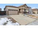 Two-car garage and a covered front porch with stone accents at 9661 Ceylon St, Commerce City, CO 80022