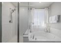Bright bathroom featuring a shower with glass door and white soaking tub by a window at 5957 N Orleans St, Aurora, CO 80019