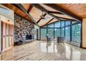 Spacious living room boasts a stone fireplace, vaulted wood ceiling, and expansive windows with picturesque views at 994 Timber Ln, Boulder, CO 80304