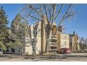 Condominium exterior featuring stone chimney and beige siding with balconies and mature tree at 4866 S Dudley St # 2, Littleton, CO 80123