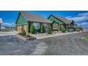 Green home exterior with an attached garage, mature trees, and manicured landscaping at 55610 E 40Th Ave, Strasburg, CO 80136