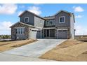 A charming new two-story home featuring stone accents, gray siding, a driveway, and a manicured lawn at 13710 Emerald Lake St, Parker, CO 80138