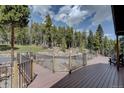 Spacious wooden deck with metal railing overlooking a serene wooded landscape at 32091 Black Widow Dr, Conifer, CO 80433