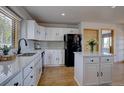 Charming kitchen with white cabinets, marble countertops, and a black refrigerator at 32091 Black Widow Dr, Conifer, CO 80433