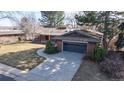 View of the brick home featuring a two-car garage, with beautiful landscaping and mature trees at 178 E 11Th Ave, Broomfield, CO 80020