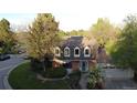 Aerial view showcasing the home's brick facade, lush landscaping, and two-car garage, situated in a well-treed lot at 10158 E Fair Cir, Englewood, CO 80111