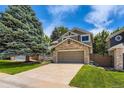 Beautiful home featuring a stone accent over the garage, complemented by a large tree and well-kept lawn at 7166 Newhall Dr, Highlands Ranch, CO 80130