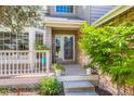 Inviting front porch with a warm welcome sign, stone facade, and a charming seating area with potted plants at 7166 Newhall Dr, Highlands Ranch, CO 80130