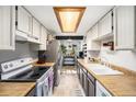 Bright kitchen with white cabinets, butcher block countertops, and stainless steel appliances at 8746 Carr Loop, Arvada, CO 80005