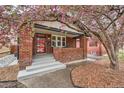 Charming red brick home with blossoming tree and inviting front porch at 1640 Harrison St, Denver, CO 80206