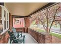 Covered front porch with red brick and green Adirondack chairs at 1640 Harrison St, Denver, CO 80206