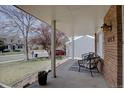 View of covered front porch featuring brick facade and patio seating area at 6719 E Costilla Cir, Centennial, CO 80112