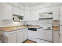 Well-lit kitchen with white cabinetry, neutral countertops, and essential appliances at 655 S Alton Way # 5C, Denver, CO 80247