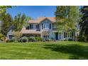 Beautiful two-story home with lush lawn, mature trees, and inviting blue front door at 4483 W Cottonwood Pl, Littleton, CO 80123