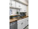 Contemporary kitchen features butcher block countertops, white cabinets, and stainless dishwasher at 3600 S Pierce St # 7-201, Denver, CO 80235