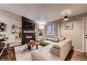 Modern living room features a fireplace with TV, comfortable sectional, stylish decor, and lots of light at 4063 S Quintero Way, Aurora, CO 80013