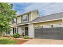Two-story home boasts a white brick facade, green siding, black shutters, and an attached garage at 16051 E Alabama Dr, Aurora, CO 80017