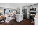 Open-concept living space with hardwood floors, kitchen with island, and modern appliances at 2399 E 99Th Way, Thornton, CO 80229