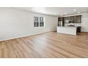 Open living room and kitchen space featuring wood-look floors and large windows at 6531 N Malaya St, Aurora, CO 80019
