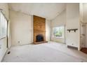 Spacious living room featuring a classic brick fireplace, bright natural light, and neutral carpeting throughout at 8552 Gray Ct, Arvada, CO 80003