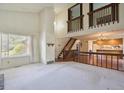 Open-concept living area with hardwood floors, large windows, staircase with wood railing, and kitchen view at 8552 Gray Ct, Arvada, CO 80003
