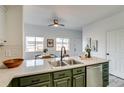 Bright kitchen features green cabinetry and an island with a stainless steel sink at 2642 Devonshire Ct, Denver, CO 80229