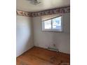 Bedroom with hardwood floors, a window, neutral walls, and baseball wallpaper border at 8250 Ralph Ln, Denver, CO 80221