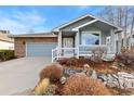 A charming home with a front porch, brick accents, a well-manicured yard, and an attached garage at 742 Megan Ct, Longmont, CO 80504
