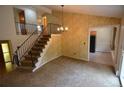 Carpeted living room featuring a staircase with an ornate railing and decorative wallpaper at 8450 Mason Cir, Westminster, CO 80031