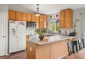 Bright kitchen features oak cabinets, white appliances, and an island, creating a cozy and functional space at 3312 Meadow Ave, Broomfield, CO 80020