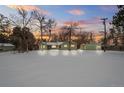 Attractive green Ranch home with snowy yard at sunset at 1876 S Chester Cir, Denver, CO 80247