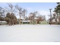 Green Ranch home with detached garage, snowy yard, and trees at 1876 S Chester Cir, Denver, CO 80247