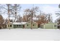 Green Ranch style home with detached garage and snowy front yard at 1876 S Chester Cir, Denver, CO 80247