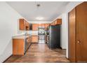 Kitchen with wood cabinets, stainless steel appliances, and laminate floor at 300 S Clinton St # 10C, Denver, CO 80247
