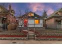 Inviting home featuring a stone accent wall, fenced yard, and blooming tree, all beautifully illuminated at dusk at 2767 W 38Th Ave, Denver, CO 80211
